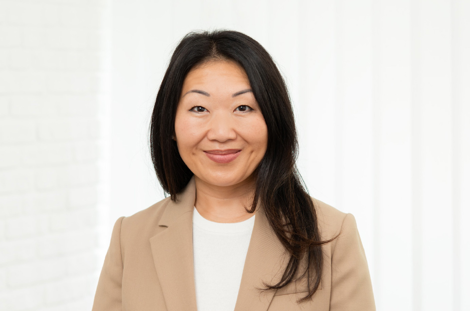 Professionelles Porträt einer Frau mit langen, dunklen Haaren, die einen beigen Blazer trägt. Der Hintergrund ist hell und neutral, was die Seriosität des Bildes unterstreicht. Ideal für geschäftliche Profile oder Unternehmenswebseiten.